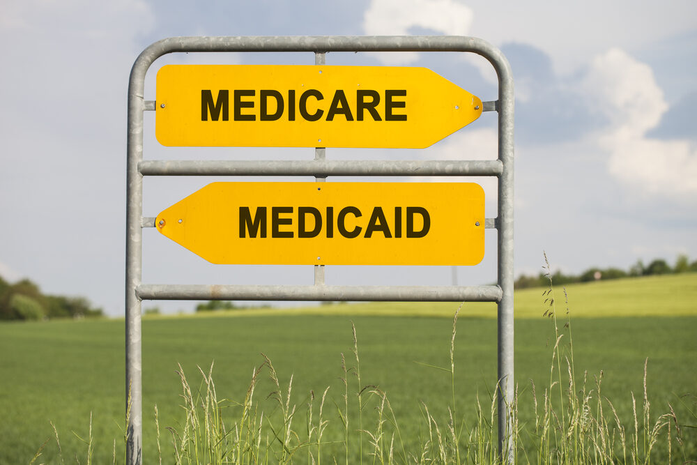 two yellow direction signs with arrows and the words medicare and medicaid