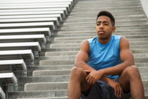 Young african american student athlete sitting on stairs in stands