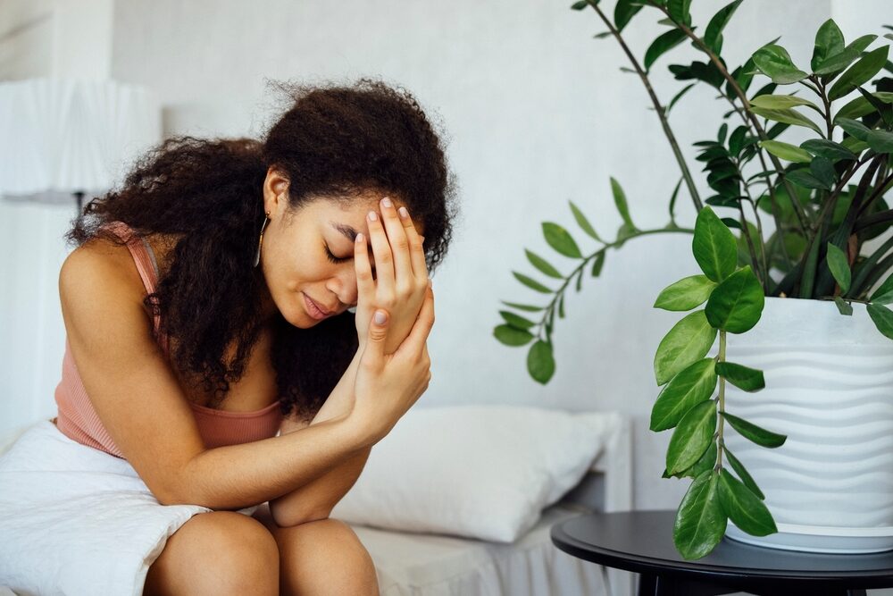 Young black woman suffering from headache or migraine after waking up in morning.