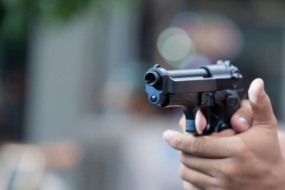 Man holding gun aiming pistol in hand ready to shoot.