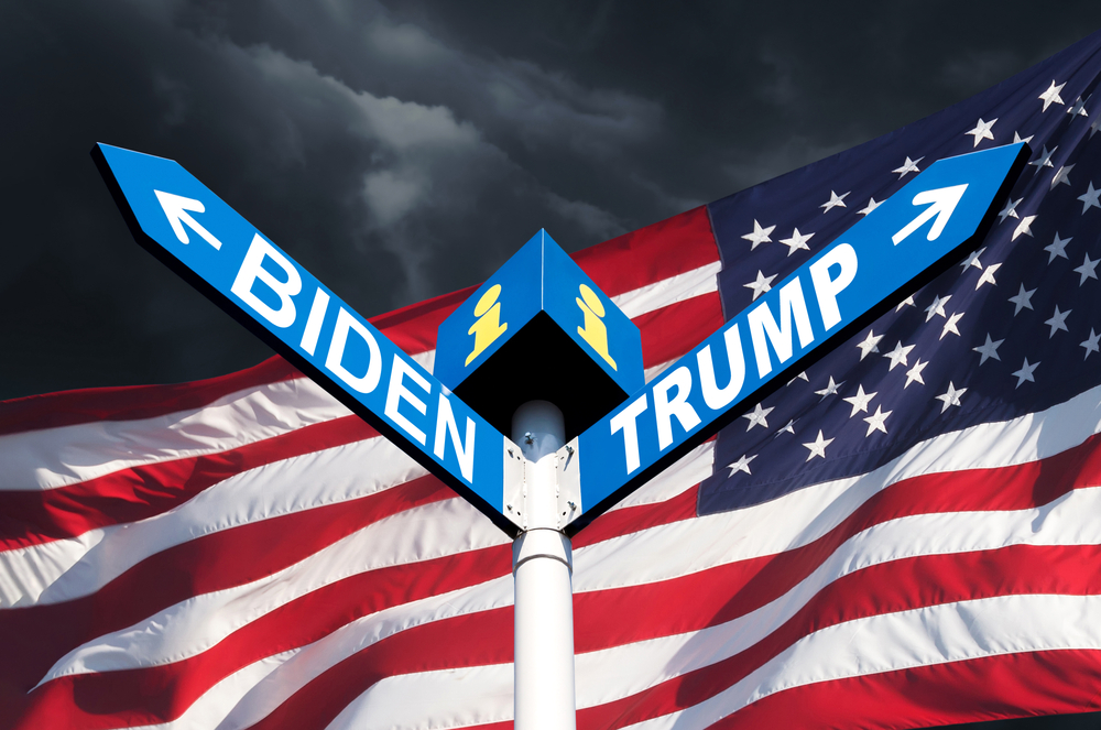 The names of Presidents Donald Trump and Joe Biden on the roadside sign on the background of the American flag and a stormy sky