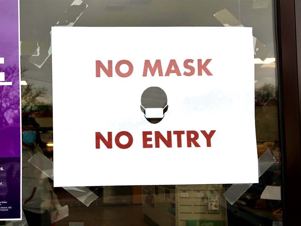 "No Mask No Entry" sign taped to a storefront in Queens, NY