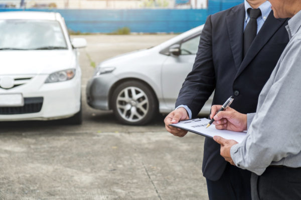 An insurance inspector assessing a damaged vehicle at the accident scene