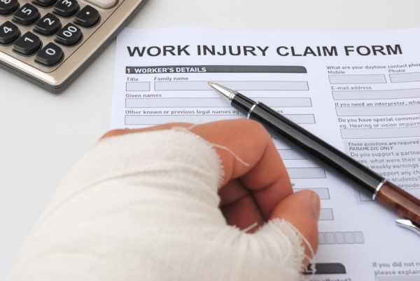 hurt hand and work injury claim form with pen & calculator