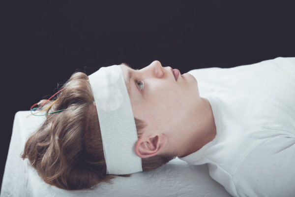 young teenage boy Lying on hospital bed with gauze bandage wrapped around head