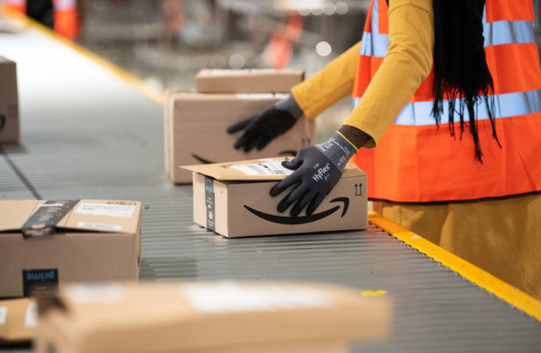 Packages are sorted by amazon workers on conveyor