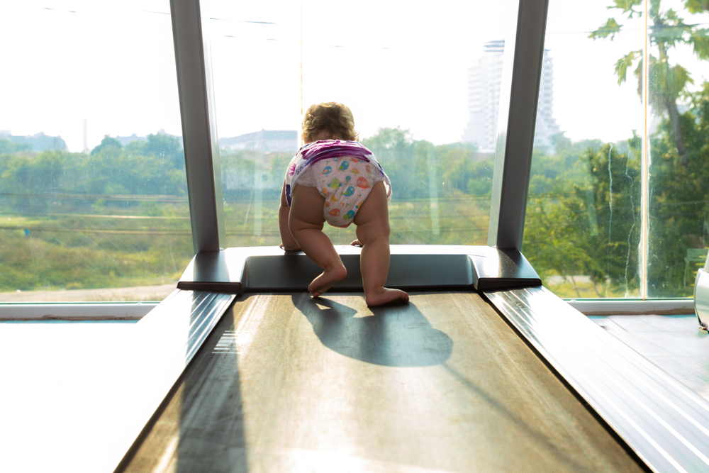 baby crawling on the treadmill in the gym with a view from the window