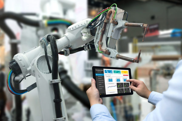 A worker adjusts the settings on an automated robot on the factory floor