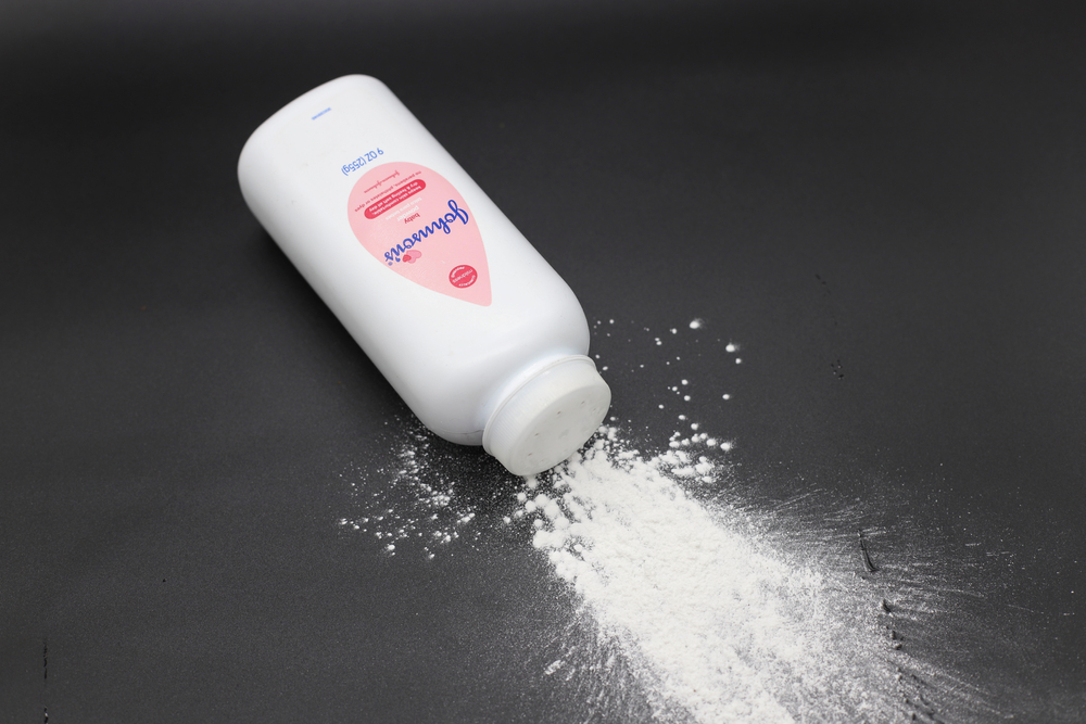 Close up image of white bottle of Johnson's baby powder isolated on black background.