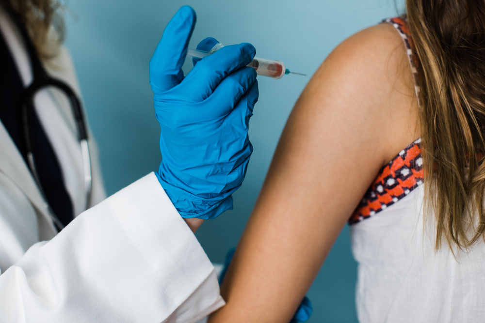 female health care worker administering a shot vaccination for a child