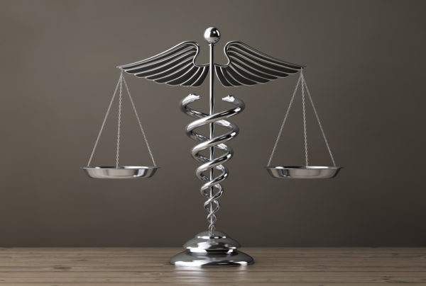 Silver Medical Caduceus Symbol as Scales on a wooden table