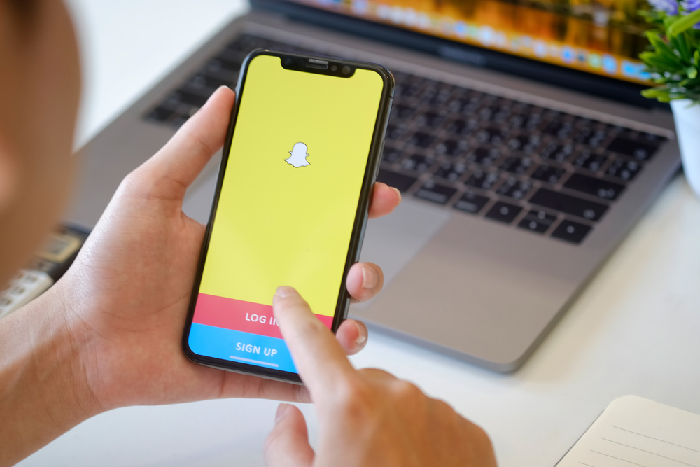 Man holding a iPhone X with social network service Snapchat on the screen.