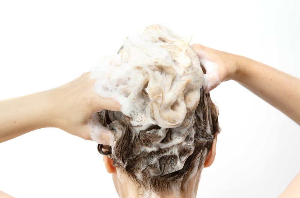 Fingers in hair with foam from shampoo.