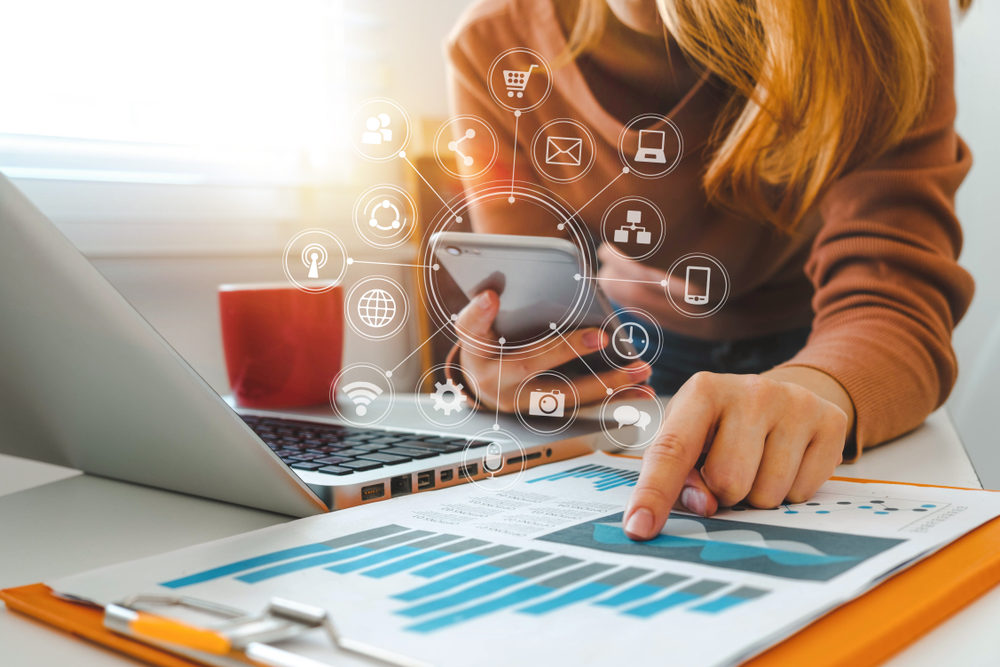 close up of businesswoman working with smart phone and laptop and digital tablet computer in modern office