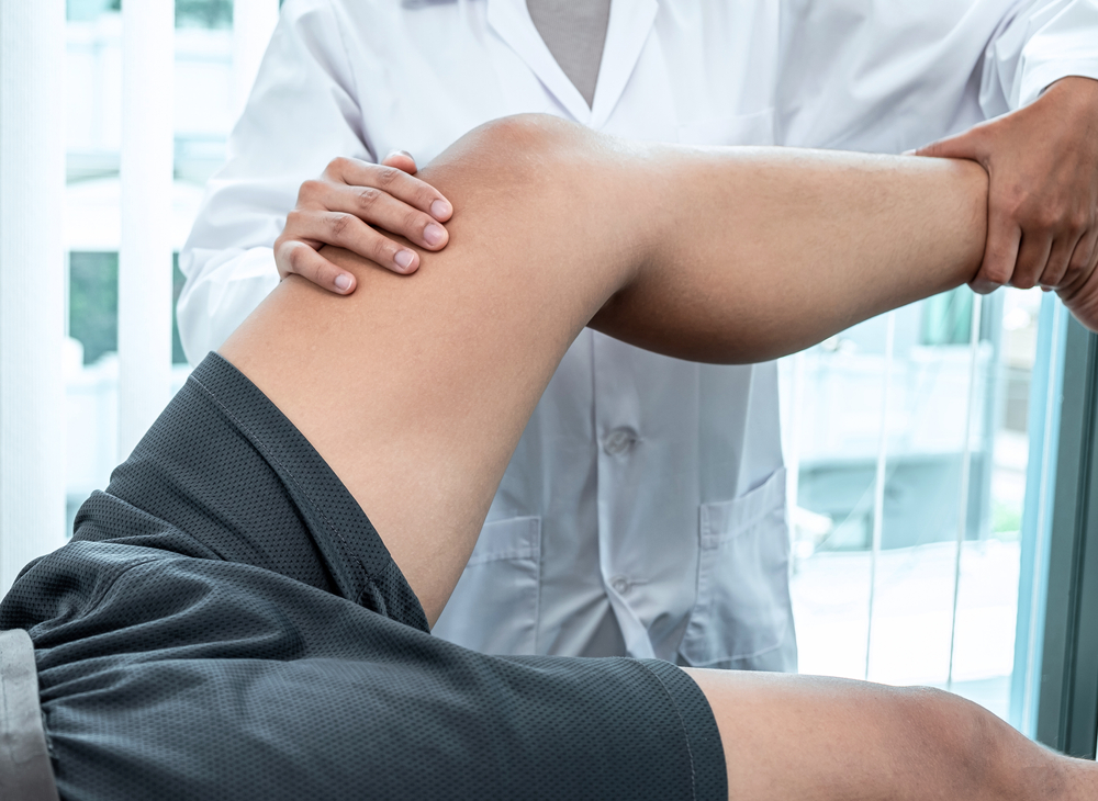 Physiotherapist working examining treating injured leg of athlete patient