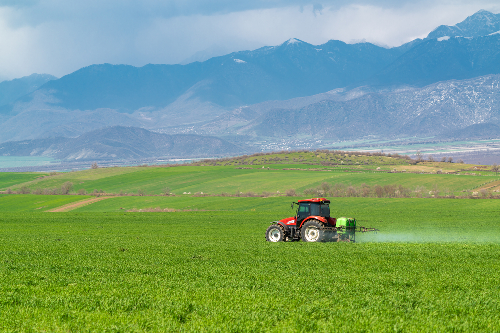 Tractor sprays a farm field with pesticides