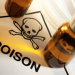 Two unlabeled vials of fluid sit on a POISON sign with skull and crossbones