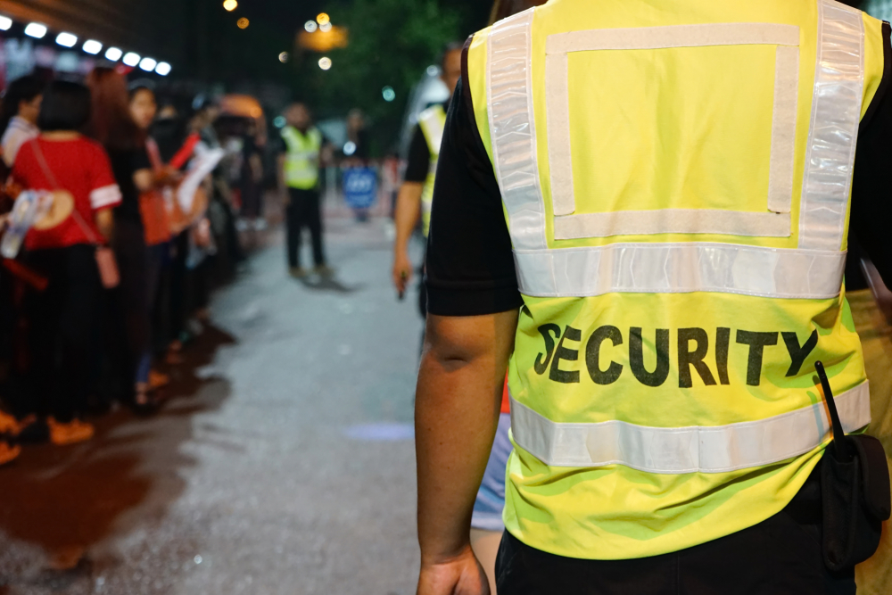 security guard with blurred crowd of audience or diversity people at concert venue entrance.