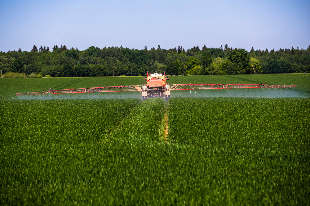 Tractor spraying pesticides on vegetable field with sprayer at spring