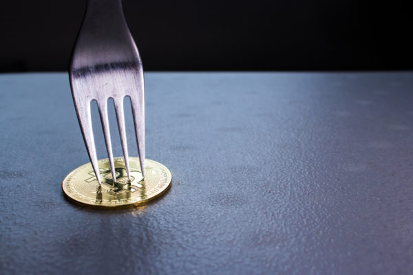 Silver fork stabbing golden Bitcoin.