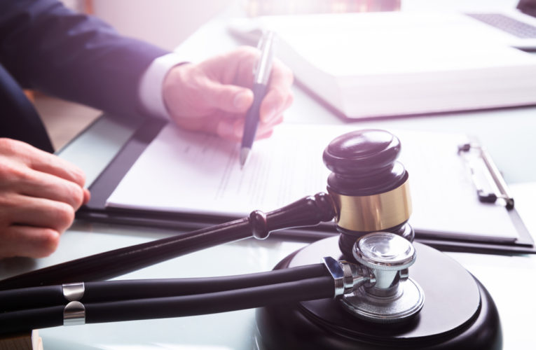 Attorney Writing On Legal Documents With Mallet And Stethoscope