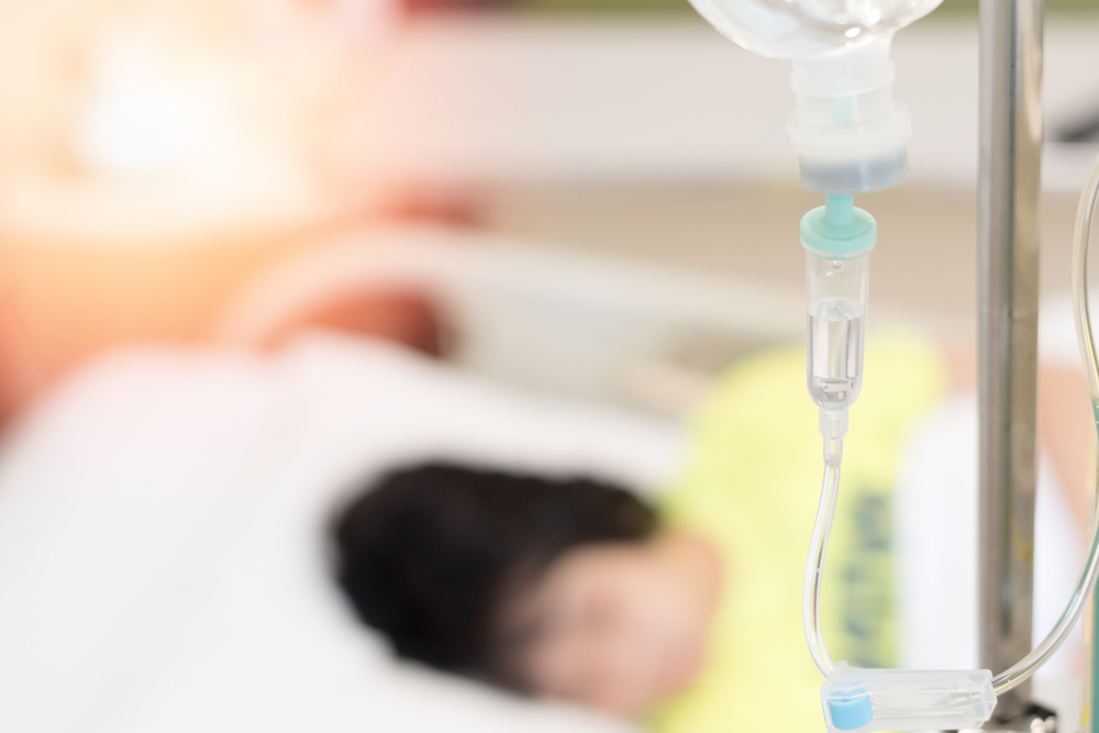 child inpatient sleeping on hospital bed with IV infusion drop