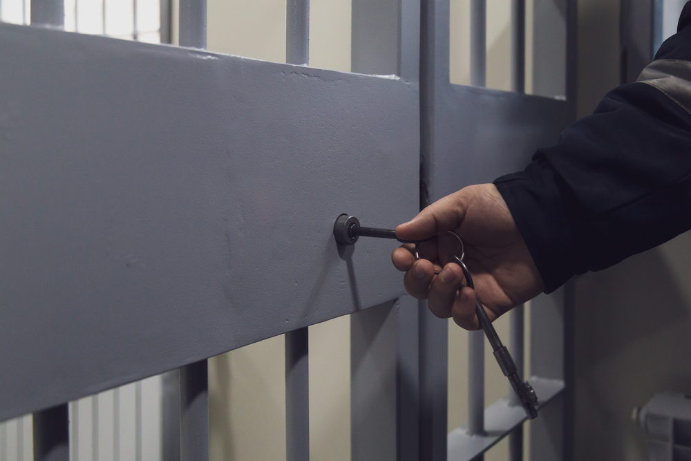 prison guard locking The door of a prison cell or detention center.