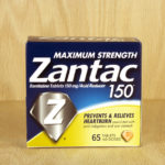 A box of Zantac acid indigestion tablets with a wood background.