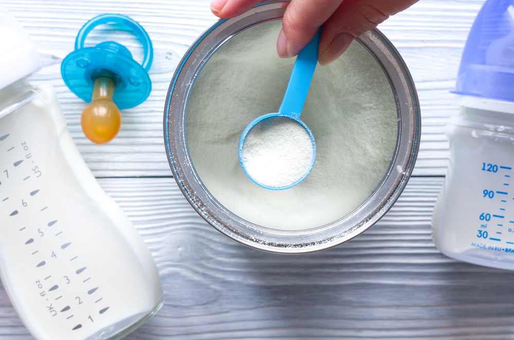 preparing baby formula on table near bottle and pacifier