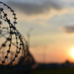 barbed wire of prison fence at sunset