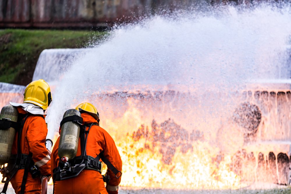 $Firefighters using Chemical foam fire extinguisher to fight with the flame from oil tanker truck accident.