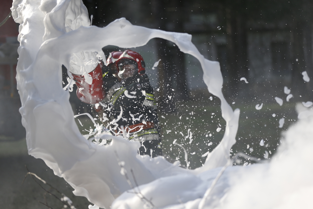 firefighter spraying foam to extinguish a fire