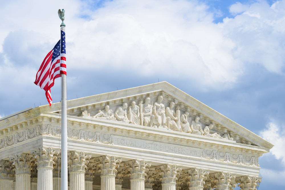 front view of United States Supreme Court Building in Washington DC with flag in forefront