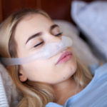 female wearing a philips respironics nasal cpap mask in bed