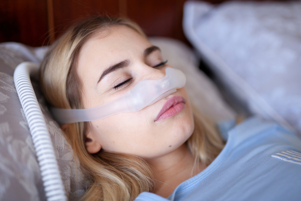 female wearing a philips respironics nasal cpap mask in bed
