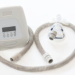 view of a cpap machine with tube and mask on white background