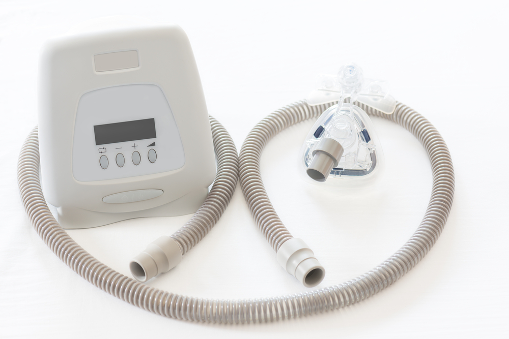 view of a cpap machine with tube and mask on white background