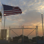 united states flag flying at a military base at dusk