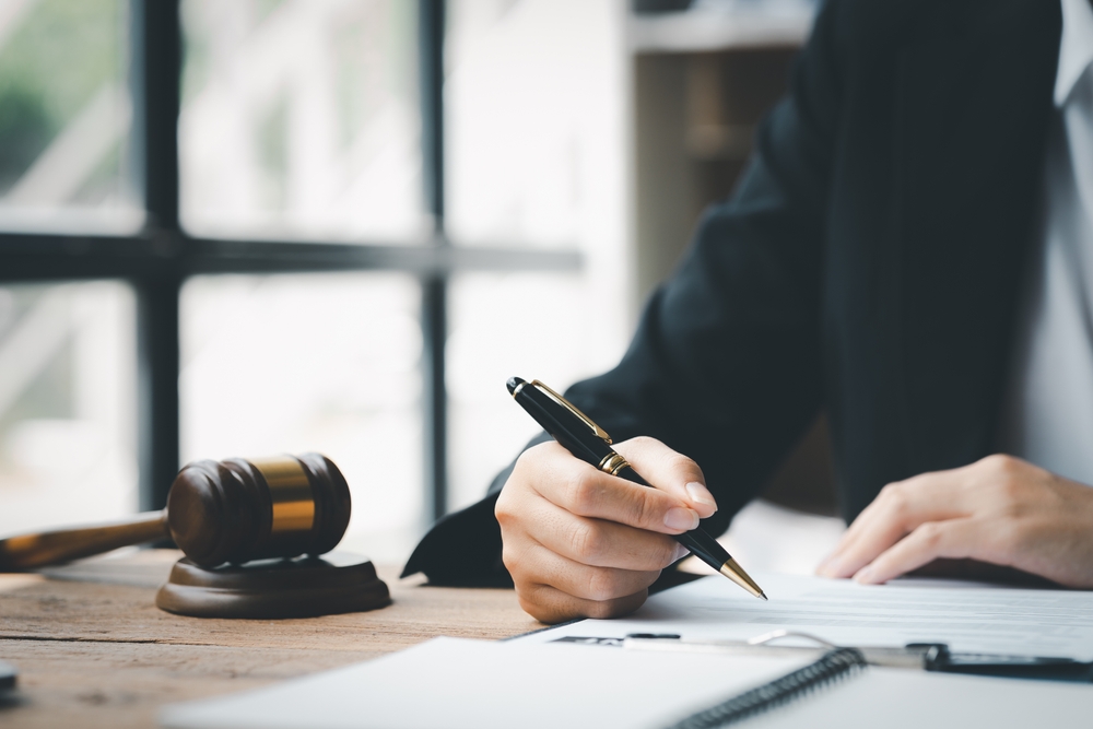 lawyer at his desk holding a pen going over paperwork for client