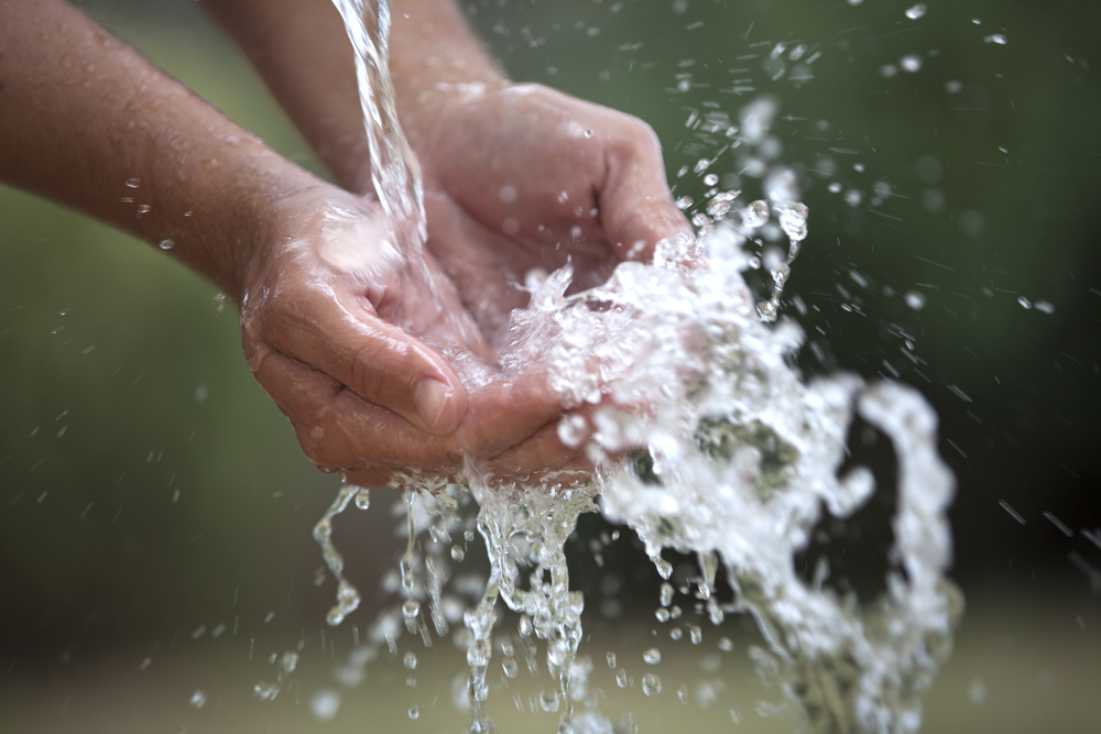 Two cupped hands feel the water splashing into them gently.