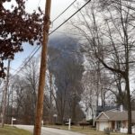 EAST PALESTINE, OH - Circa Feb 2023: The rising smoke cloud after authorities released chemicals from a train derailment as seen from the ground in a nearby neighborhood.