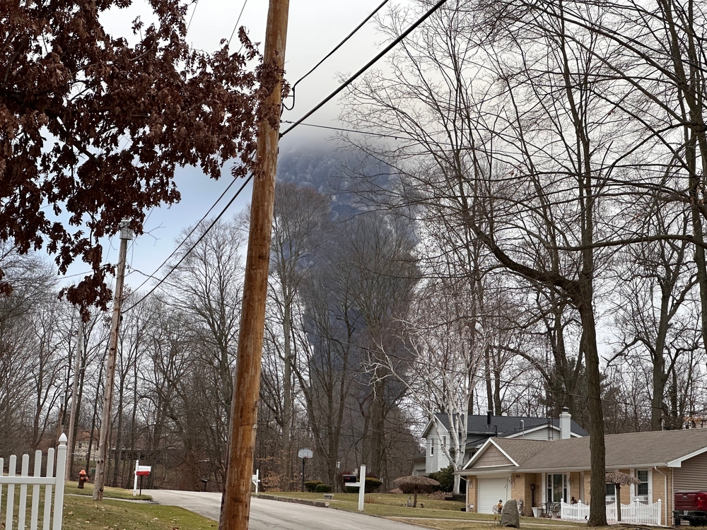 EAST PALESTINE, OH - Circa Feb 2023: The rising smoke cloud after authorities released chemicals from a train derailment as seen from the ground in a nearby neighborhood.