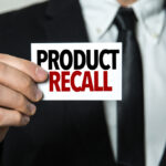 man in a suit holding a card with product recall on it
