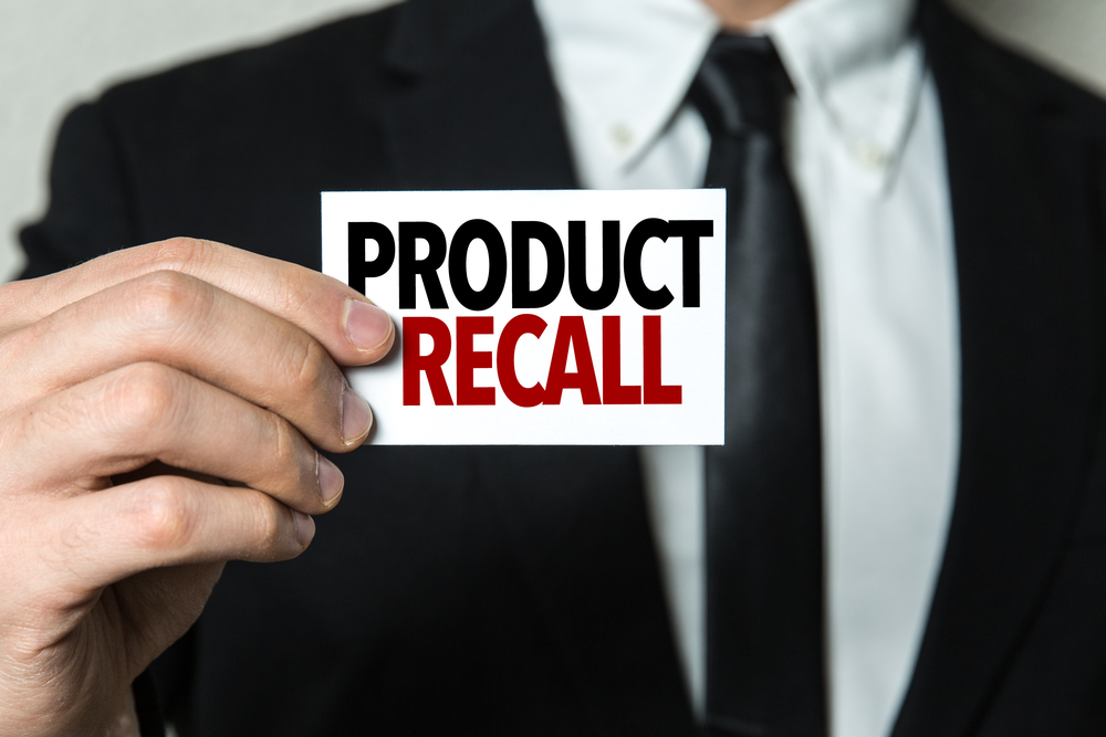 man in a suit holding a card with product recall on it