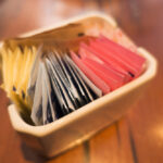 close up the selective focus of different colored and different types of sugar packets in the ceramic container