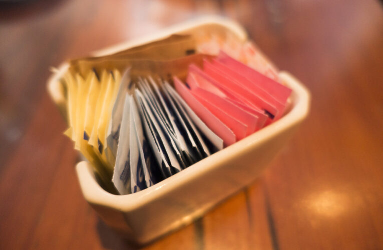 close up the selective focus of different colored and different types of sugar packets in the ceramic container