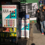 Passer-by in the Tribeca neighborhood of New York walk past a store advertising Juul brand vaping products.