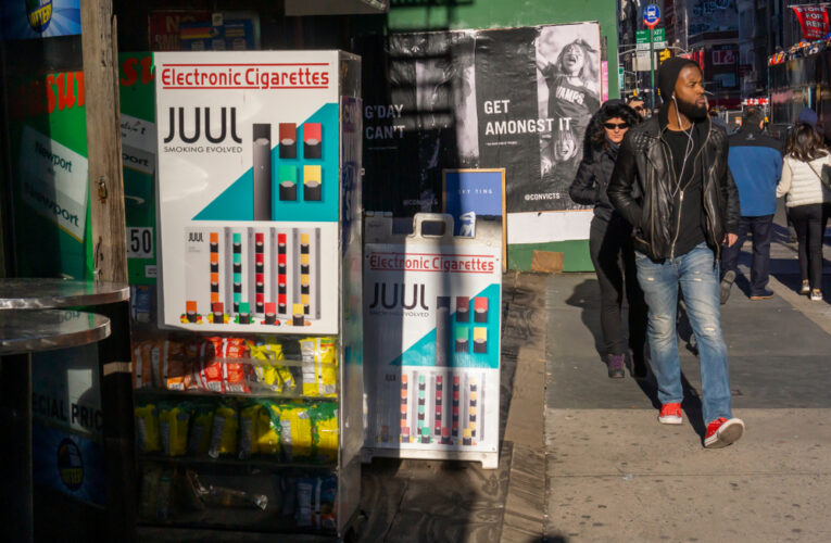 Passer-by in the Tribeca neighborhood of New York walk past a store advertising Juul brand vaping products.