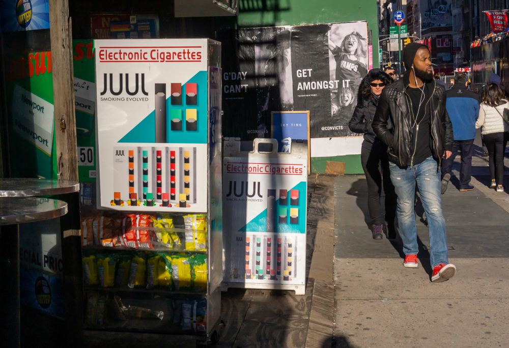 Passer-by in the Tribeca neighborhood of New York walk past a store advertising Juul brand vaping products.