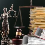 lady justice on desk piled with files with scales and gavel in the background